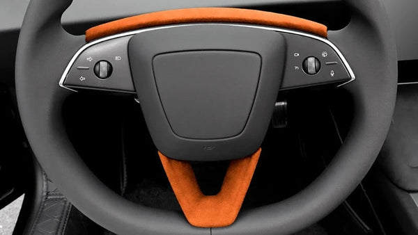 Orange U-shaped Alcantara suede steering wheel panel designed for Tesla Model 3+ with the interior of a car steering wheel in the background.