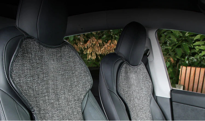 Car interior with gray textured seat covers and a view of greenery outside.