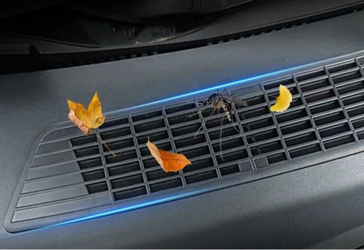 A black protective cover for the air inlet of a vehicle, featuring a semi-transparent insect-proof net design, displayed with autumn leaves尝试着穿过网状物卡住, highlighting the need for protection.