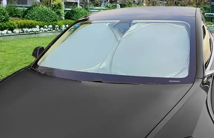 Car sunshade on a car window with a garden and building in the background